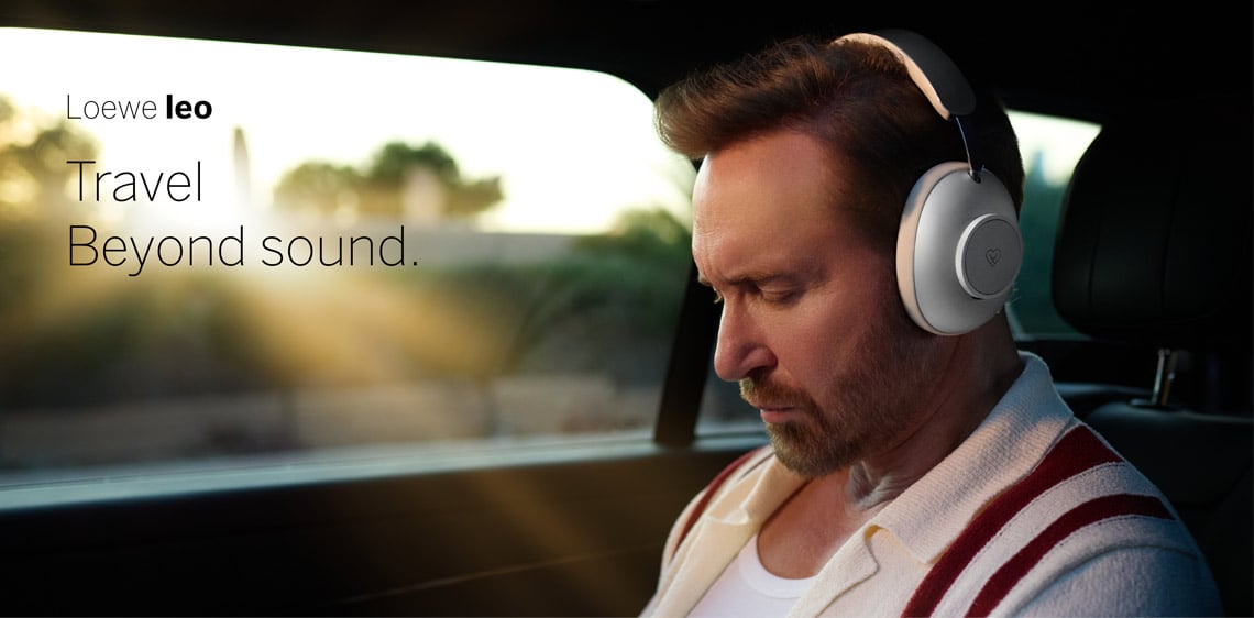 Mann trägt Loewe leo Over-Ear-Kopfhörer während einer Autofahrt – Travel beyond sound.