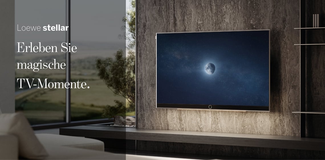 Loewe Stellar Fernseher an einer Wohnzimmerwand mit Naturblick im Hintergrund.
