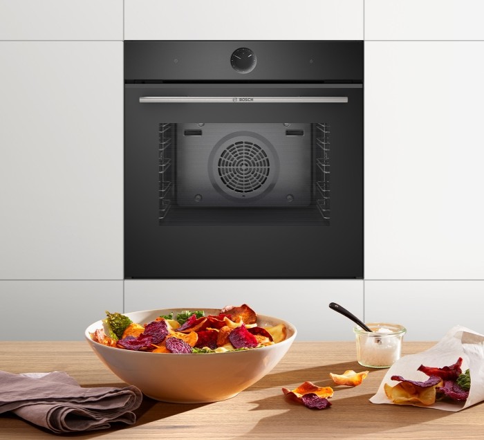 Einbaubackofen mit AirFry-Technologie, präsentiert mit frisch zubereiteten Gemüsechips und Dip.
