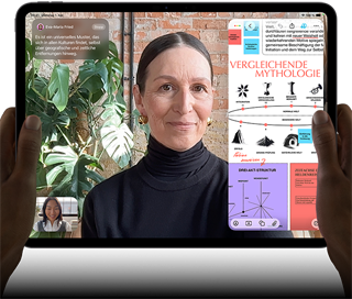 iPad Pro, Vorderansicht, Querformat, Farbe Space Schwarz, gerundete Ecken, schwarzer Displayrand, zwei Hände halten es an der linken und rechten Seite, das Display zeigt ein FaceTime Gespräch, das live übersetzt wird, und eine Lernapp zeigt eine Präsentation zum Thema „Vergleichende Mythologie“ mit Text, Diagrammen und handschriftlichen Notizen